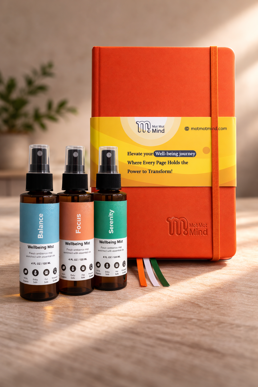 Three bottles of 'Wellbeing Mist' with an orange notebook on a wooden surface.